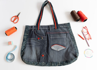 Denim bag and sewing accessories on white background