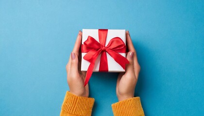 female hands holding gift box on blue background
