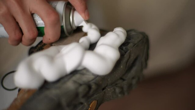 Male hands applying cleaning foam to dirty soles of dark sneakers. Process cleaning shoes from dirt and dust. Concept of caring for leather footwear. Shooting in slow motion.