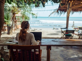 A person working on a laptop at a beachside cafe