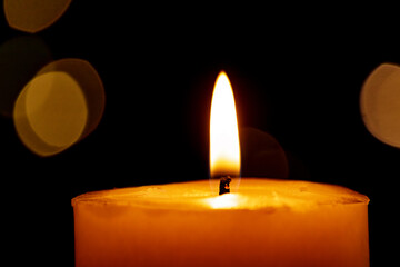Candle burns Isolated On Black background with Christmas Lights Defocused Bokeh.