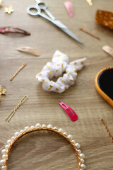 Wooden hairbrush, scissors and various headbands, hair clips and scrunchies on wooden background. Selective focus.