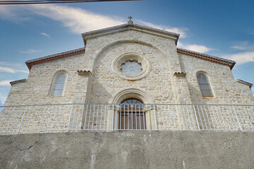 Fototapeta na wymiar This image showcases the front facade of a serene stone church located in the picturesque Ardeche region. The church, constructed with traditional stonemasonry, presents a robust and time-honored