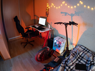 Hipster room. a workplace with a computer. electric scooter and monocycle. neon light © pavelkant