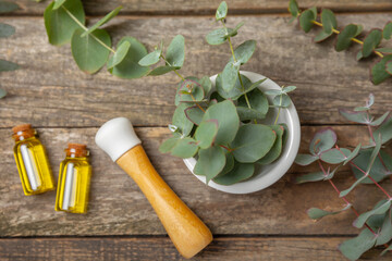 Eucalyptus leaves and mortar on a wooden background.Spa concept.Ingredients for alternative medicine and natural cosmetics. A bottle of essential oil and a bunch of eucalyptus. Organic skin care 