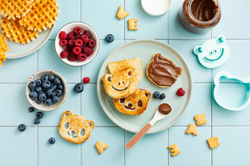 Children's breakfast. Toasted bread in the form of a panda and frog with chocolate paste and berries. Top view, flat lay.