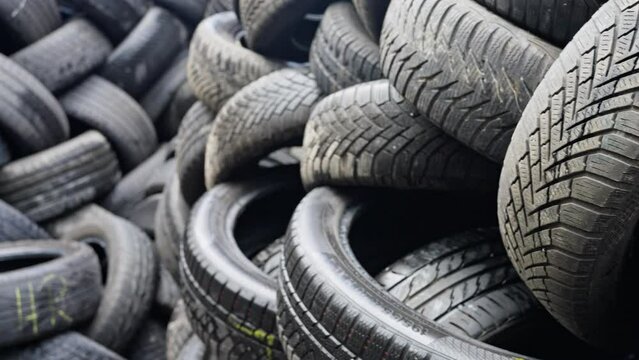 Different tread pattern on rubber. Old tires warehouse. Old car tires stacked in a warehouse close-up. Slow motion.