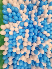 In the children's playground there are many small white and blue plastic balls arranged for children to play with for recreation. Hollow plastic ball texture background. Play toy for kids activity. 
