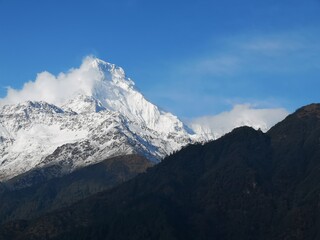 A majestic snow-capped mountain rises against a pristine blue sky, creating a breathtaking winter wonderland.