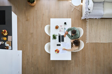Middle aged man and woman using laptop computer sitting at table in living room interior. Mature...