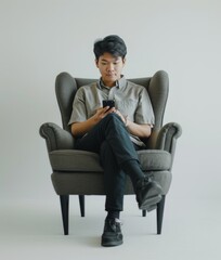 Fototapeta na wymiar Man Sitting in Chair, Using Cell Phone