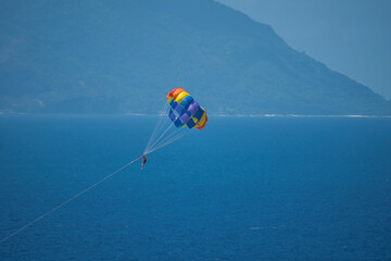Single person paragliding from boat at beau vallon beach, Mahe, Seychelles 