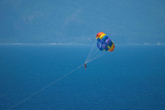 Single person paragliding from boat at beau vallon beach, Mahe, Seychelles 