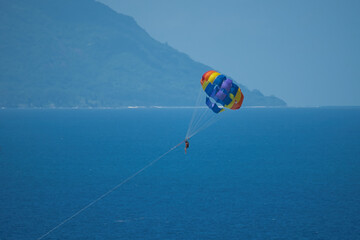 Single person paragliding from boat at beau vallon beach, Mahe, Seychelles 