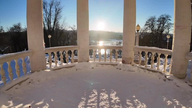White columns over a frozen lake with white snow in winter and glowing bright sun