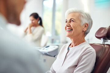 Cute elderly gray-haired woman smiling with white teeth, sitting in dental chair in the clinic. Concept of dental treatment, health, consultation with an orthodontist, stomatology, medical care