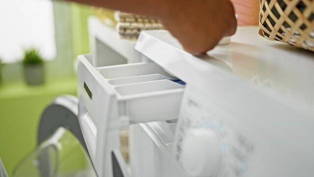 Closeup of a person adding detergent to a washing machine in a bright laundry room.