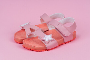 Two pink sandals on pink background. Cute pink sandals for little girl.