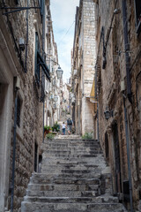 Fototapeta na wymiar Narrow and steep alley with stone steps in the center of the old town of Dubrovnik, Croatia