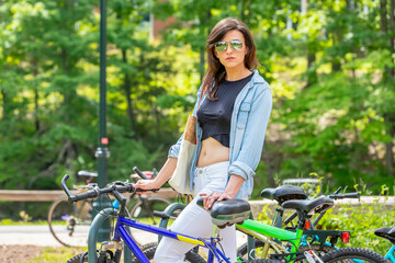 Fototapeta na wymiar Chic Commute: Stunning Brunette College Student's Effortless Arrival on Campus by Bicycle, Poised and Prepared for Classes