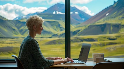 female short haired freelancer working on her laptop in her home office, in the background is a serene and calm mountain view