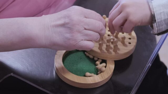 disabled elderly woman 75s after stroke one hand plays with grandson wooden chips, intergenerational communication, fine motor skills training, prevention dementia disease, support in old age