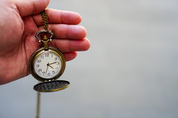 Man's hand holding a pocket watch and blurred background