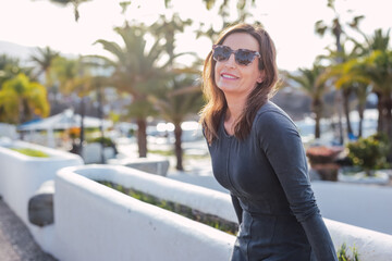 Smiling 40 year old woman strolling through streets with sunglasses