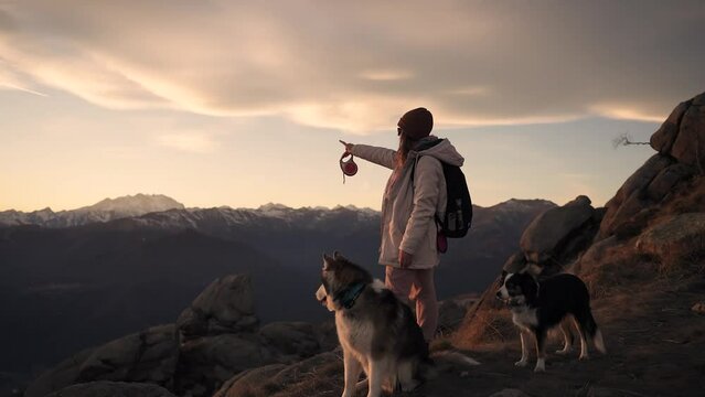 A girl walking in the mountains with her dogs at sunset.