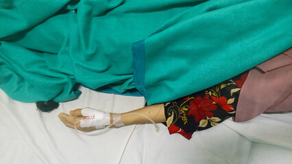 Hospital, Jakarta 5 February 2024. A middle-aged woman's hand is on an IV drip and lying on a hospital bed