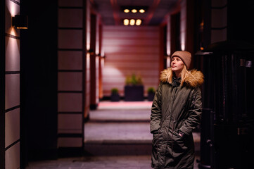 Woman takes a contemplative walk in an illuminated city alley at night, with warm lights above