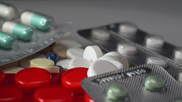 White medical pills, red and green capsules rotating in 4K. Pills, drugs, supplements, vitamins rotating