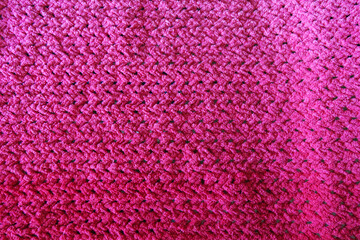 Textures of this close-up of a pink crocheted blanket.