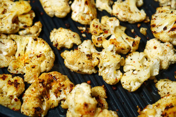 Grill showcasing mouth watering cauliflower cooking to perfection and sizzling with crispy goodness.