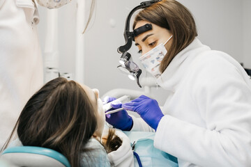 Fototapeta premium A young woman is undergoing treatment in a modern dental clinic. The concept of dental treatment, whitening, installation of veneers and braces, cleaning the oral cavity.