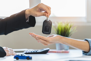 Car rental service concept. Close up view Hand of agent giving car key to customer after signed...