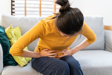 Young Asian woman suffering stomach pain from food poisoning.