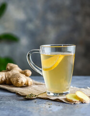 Ginger tea in a glass cup with fresh ginger root on a blurred background