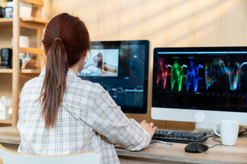 The back view of a woman sitting and editing a video at home