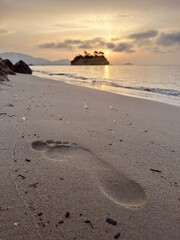 Foot imprinted in the sand against the background of the sea and islands. Cameo island in Greece. Sunrise on Cameo island in Greece. Cameo Wedding Island in Zakynthos, Greece.