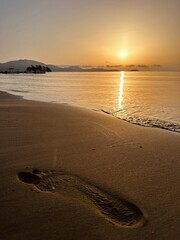 Foot imprinted in the sand against the background of the sea and islands. Cameo island in Greece....