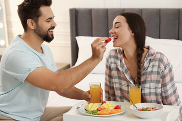 Obraz na płótnie Canvas Happy couple having breakfast on bed at home