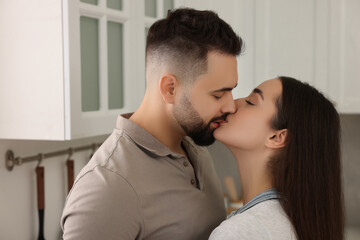 Affectionate young couple kissing in light kitchen