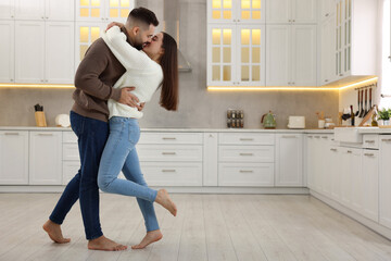 Affectionate young couple kissing in kitchen. Space for text
