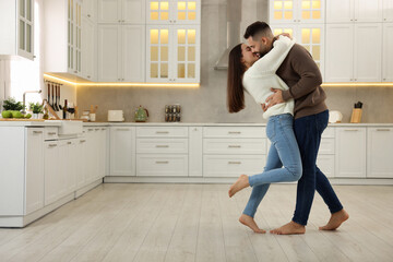 Affectionate young couple kissing in kitchen. Space for text