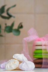 a pile of sweet meringues, on the background of a gift macaron with a ribbon and a bow