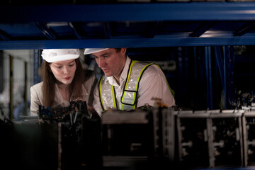 checking and inspecting metal machine part items for shipping. male and woman worker checking the...