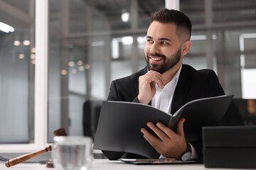 Smiling lawyer with folder in office, space for text