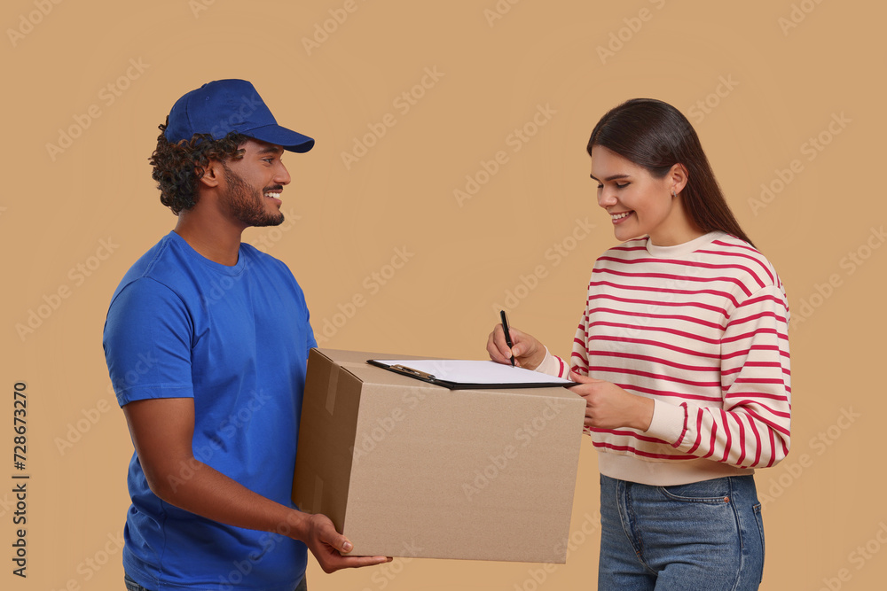 Poster Smiling woman signing order receipt on light brown background. Courier delivery