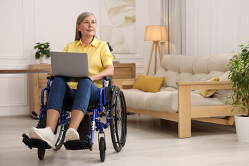 Woman in wheelchair using laptop at home